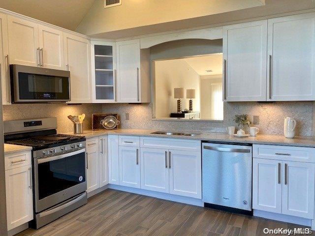 a kitchen with granite countertop cabinets stainless steel appliances and wooden floor