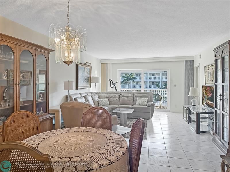 a living room with furniture a chandelier and a dining table with wooden floor