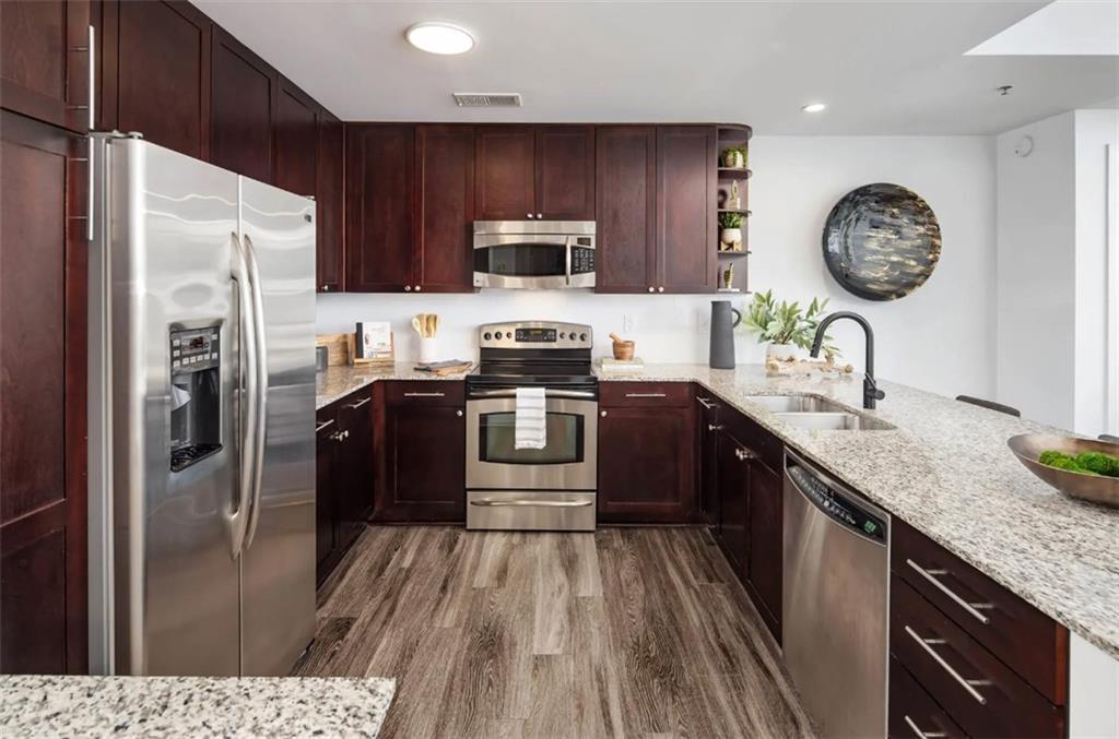 a kitchen with stainless steel appliances granite countertop a stove a sink dishwasher a refrigerator and a microwave