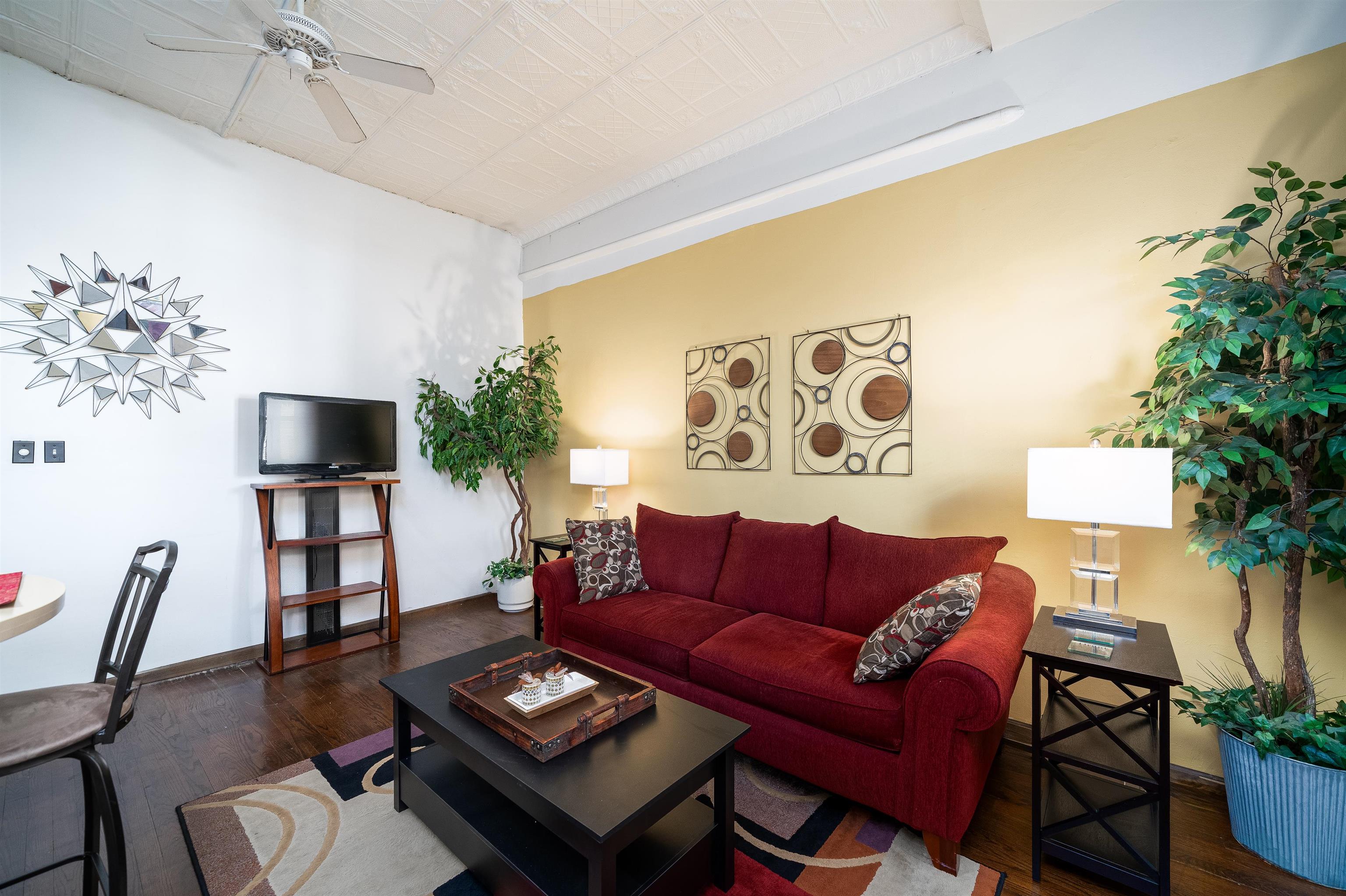 a living room with furniture a flat screen tv and a wall painting