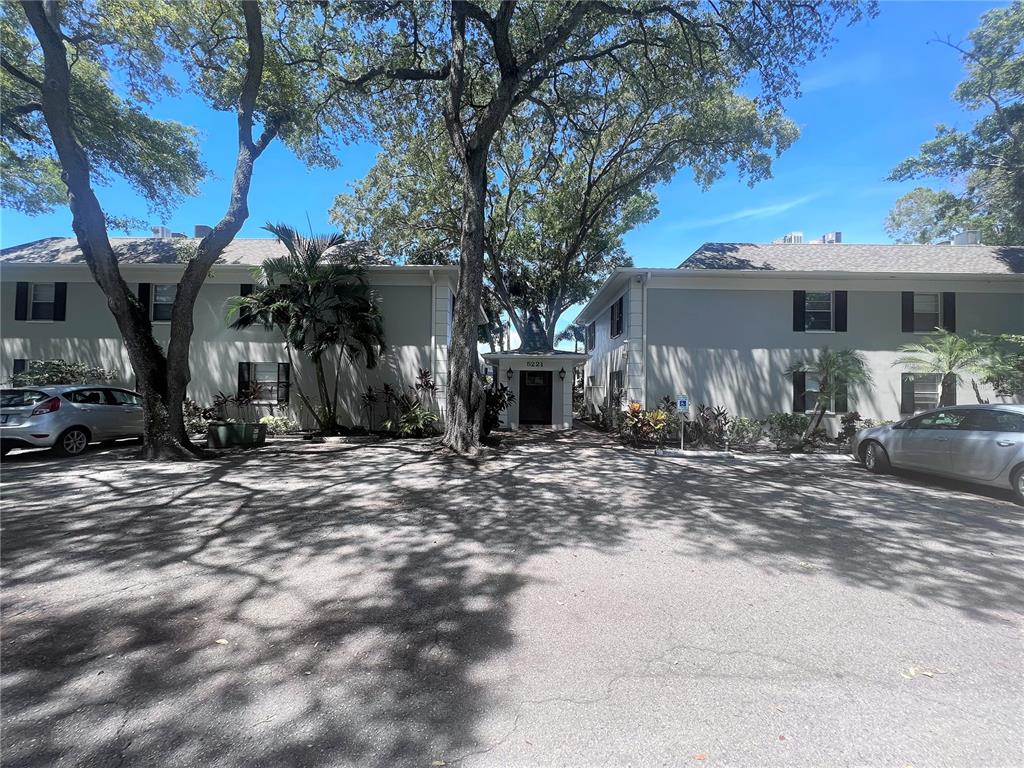 a view of a house with large tree next to a yard