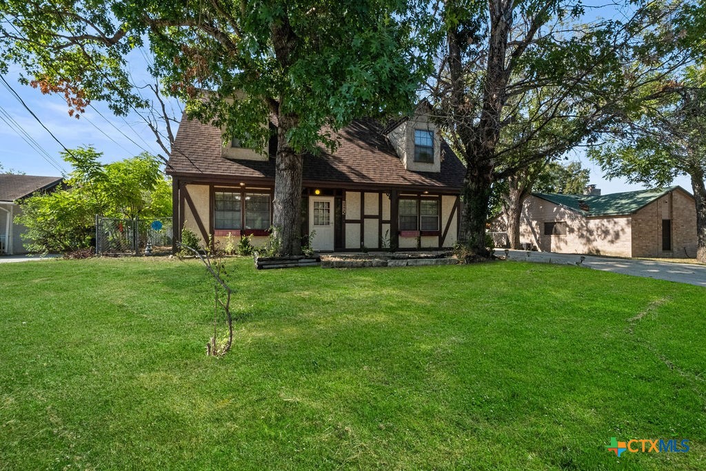 a view of a house with a big yard and large tree