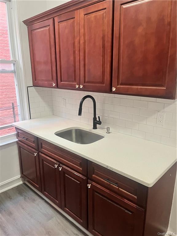 Kitchen with sink, hardwood / wood-style flooring, and tasteful backsplash