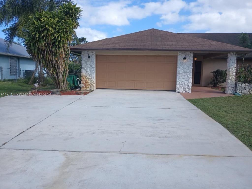 front view of a house with a yard and palm trees