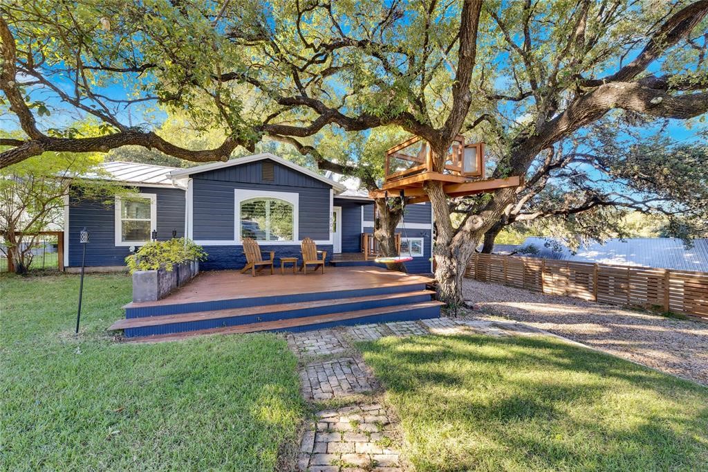 a view of a house with a yard fire pit and a large tree