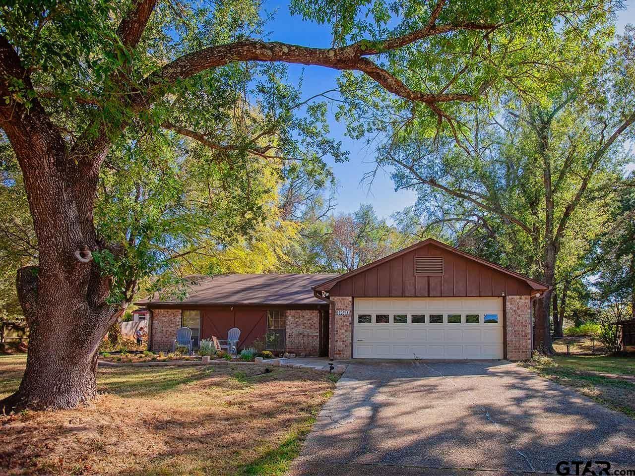 a view of a house with a yard and large tree