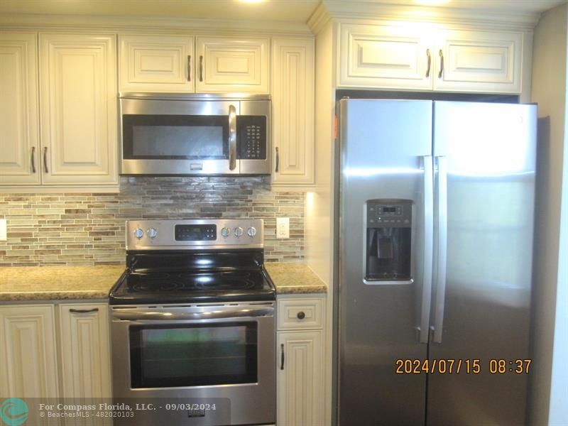 a kitchen with granite countertop a stove and a microwave