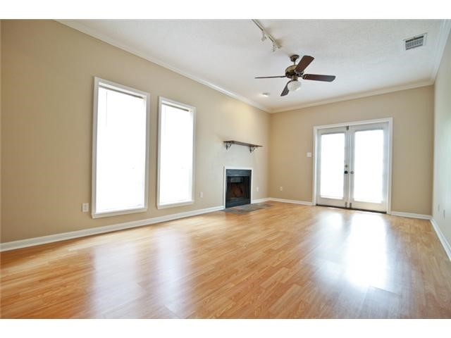 an empty room with wooden floor ceiling fan and windows