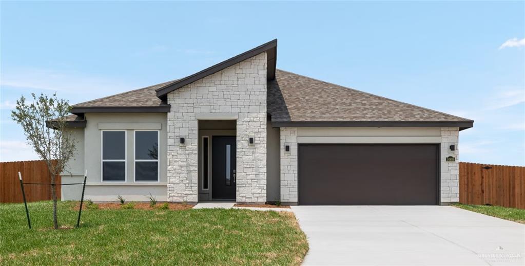 View of front of property featuring a garage and a front lawn