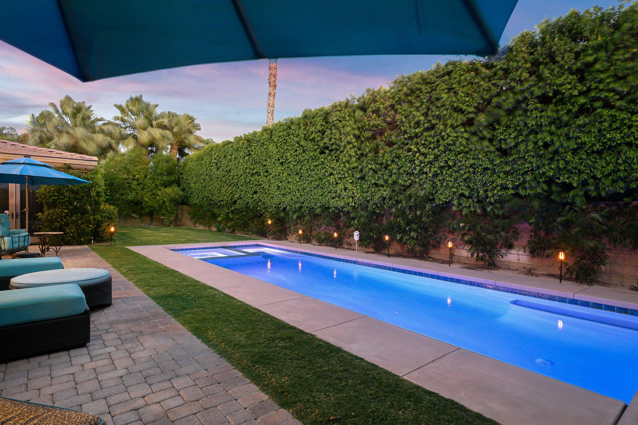 a view of a backyard with lawn chairs under an umbrella