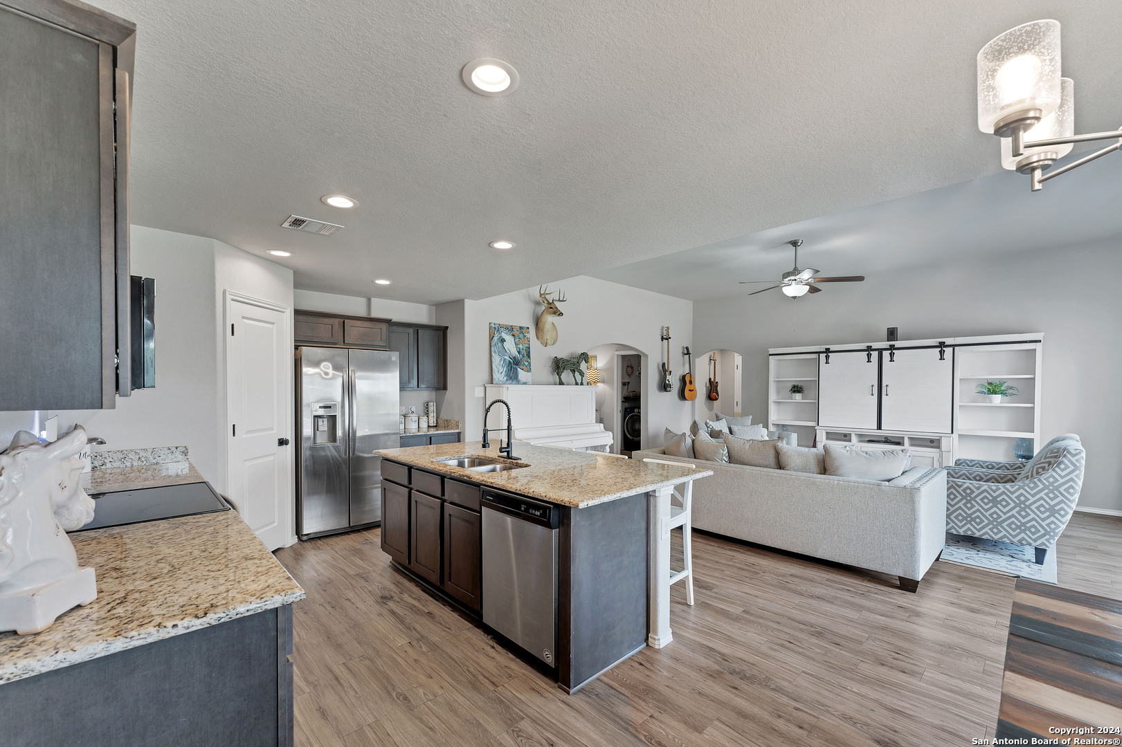 a living room with stainless steel appliances granite countertop furniture and a wooden floor