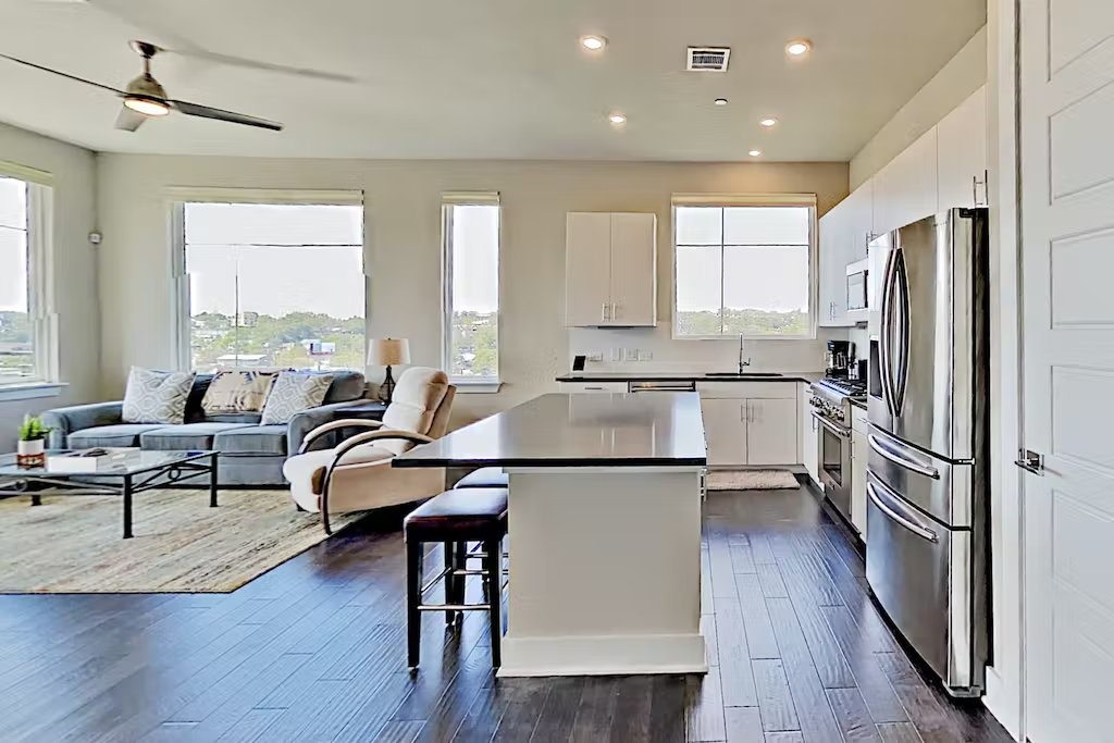 a kitchen with stainless steel appliances a refrigerator a sink dishwasher a stove and white cabinets with wooden floor