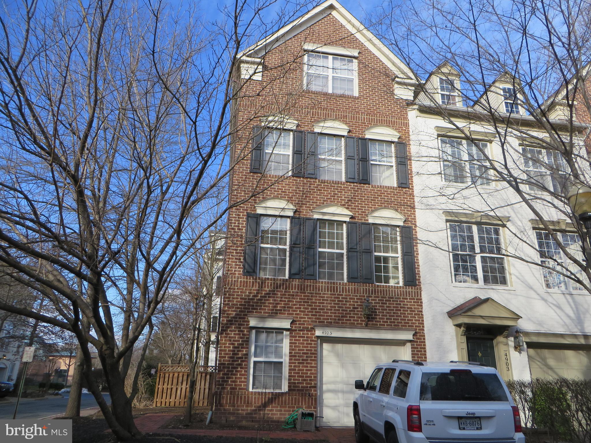 a front view of a building with lot of cars and trees