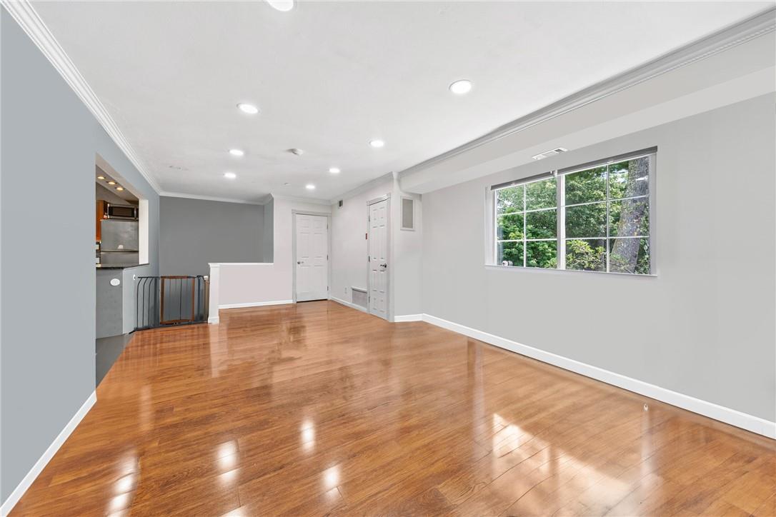 Unfurnished living room featuring hardwood / wood-style floors and crown molding