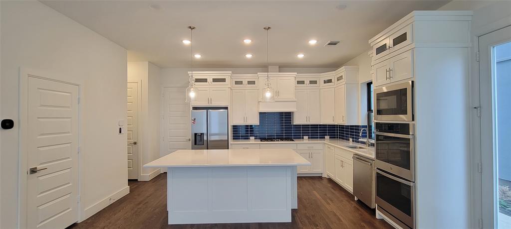 a kitchen with kitchen island a counter top space appliances and cabinets