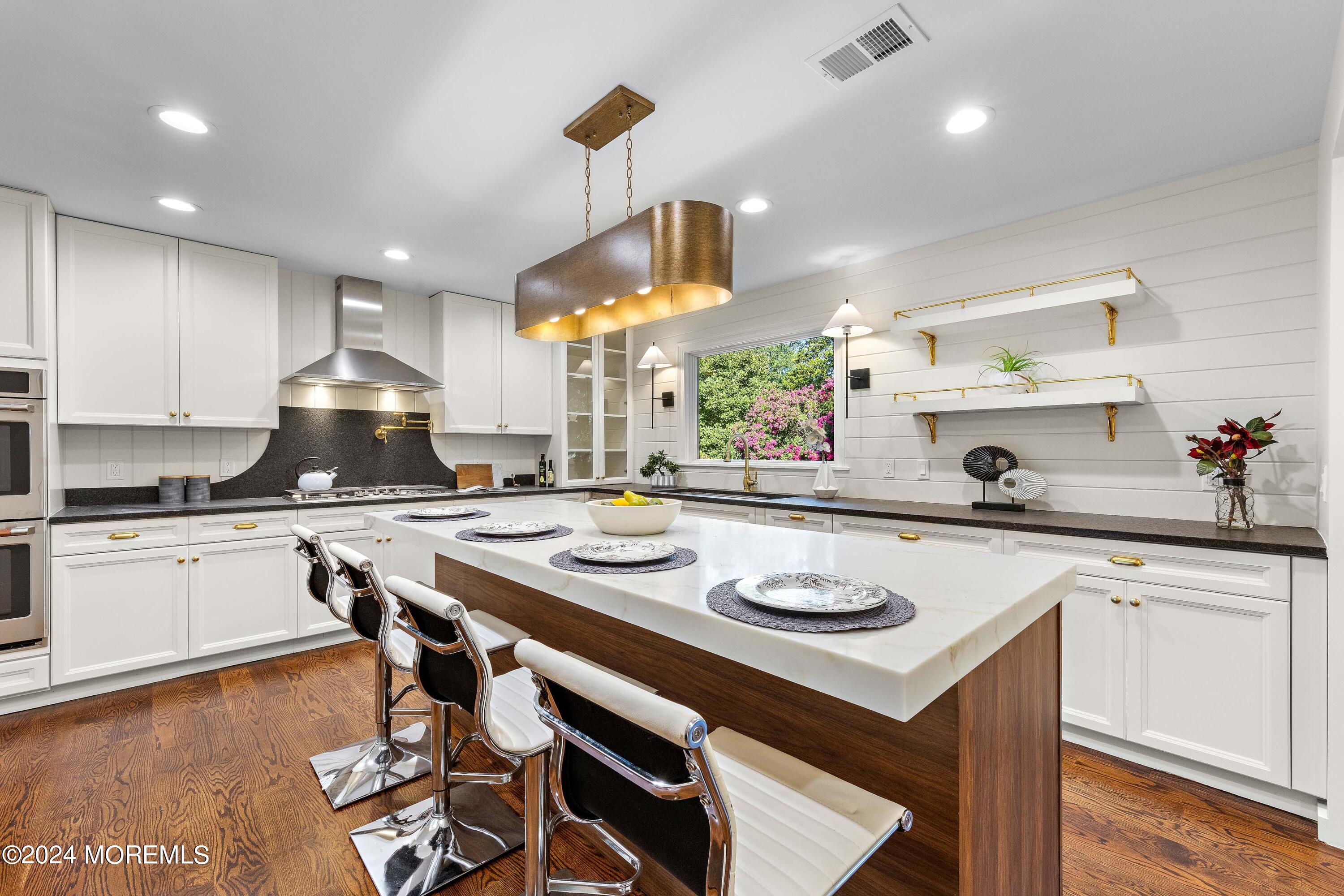 a kitchen with a sink a stove and chairs with wooden floor