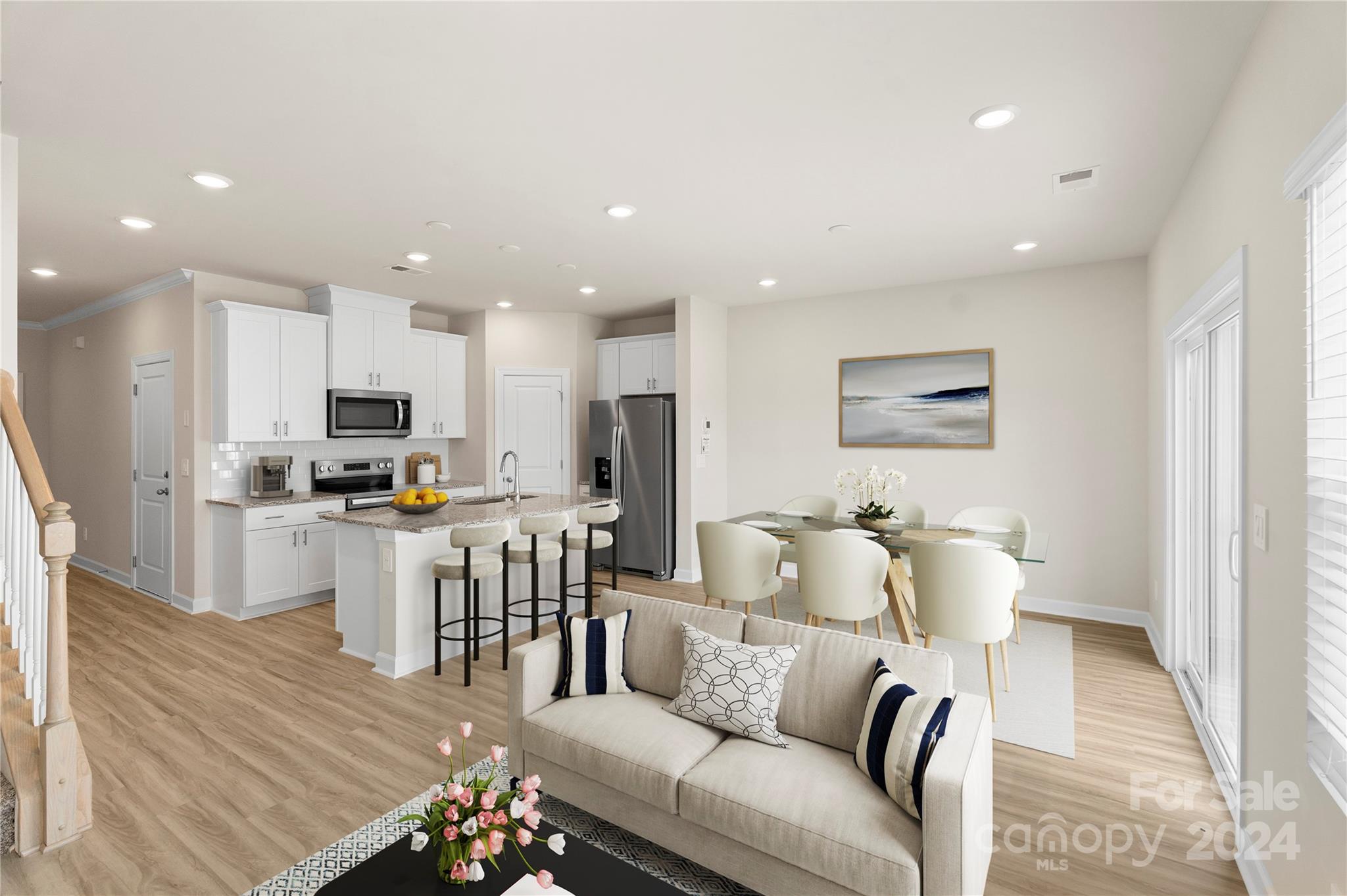 a living room with stainless steel appliances furniture wooden floor and a view of kitchen