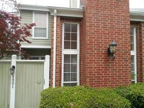 a view of a brick house with a large window and potted plants