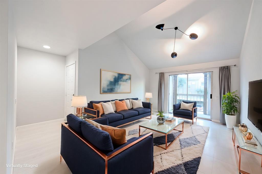 Bright, modern living room with high vaulted ceilings, sleek lighting fixtures, and sliding doors leading to the balcony.