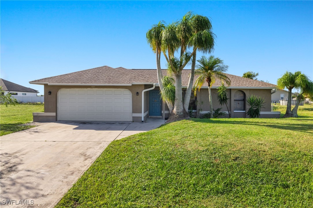 a front view of a house with a garden and palm trees