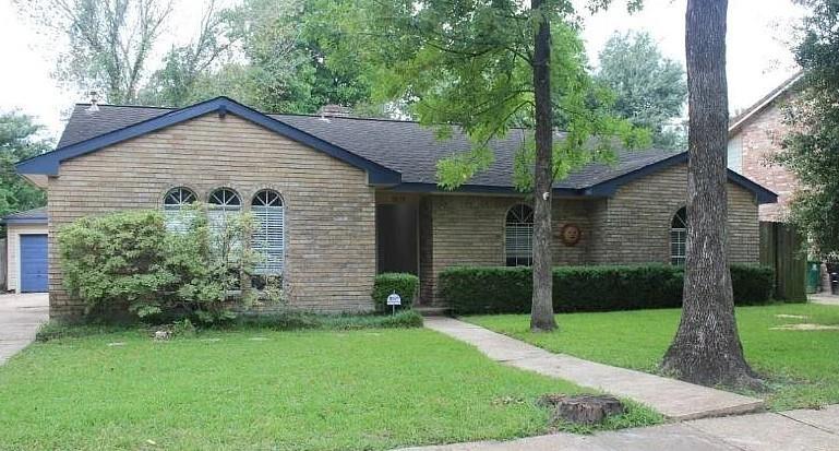 a view of a house with a yard plants and large tree