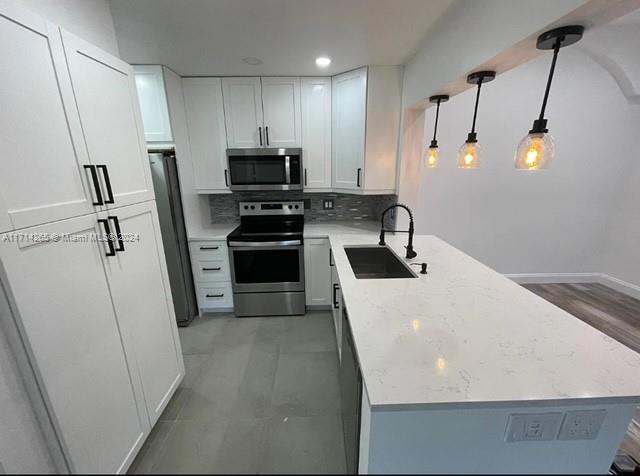 a kitchen with stainless steel appliances a refrigerator a sink a stove and white cabinets