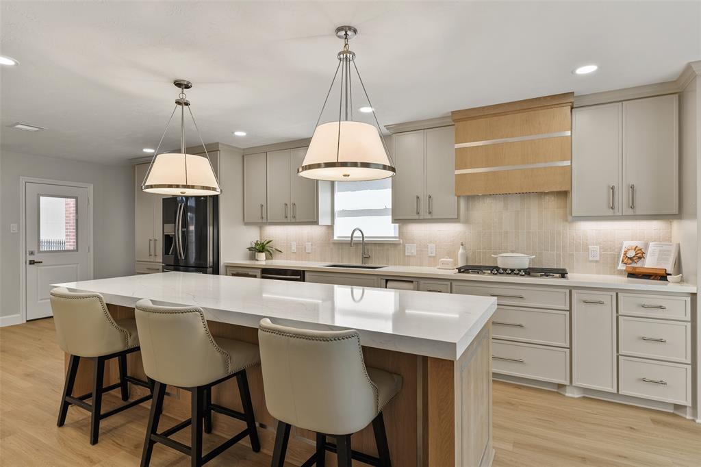 a kitchen with kitchen island granite countertop a sink a stove a dining table and chairs