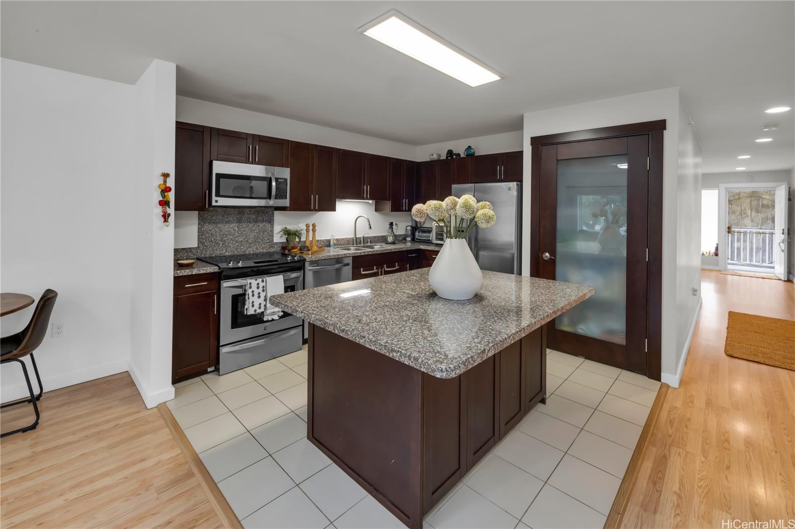 a kitchen with stainless steel appliances granite countertop a stove top oven a sink and a refrigerator