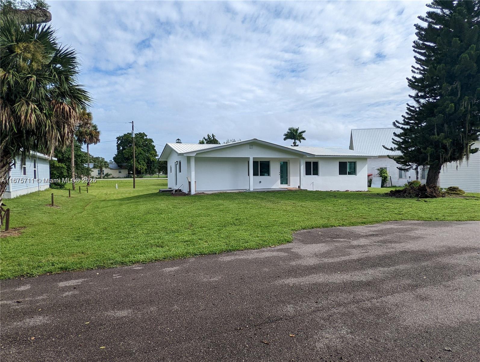 a view of a house with a big yard and palm trees