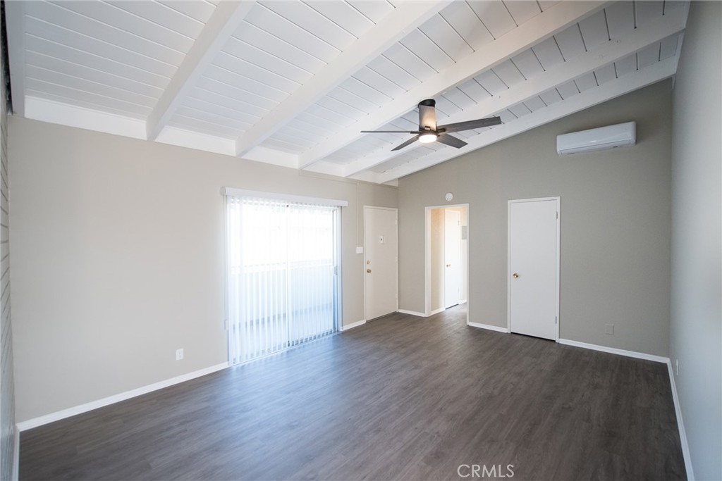 a view of an empty room with wooden floor and a ceiling fan