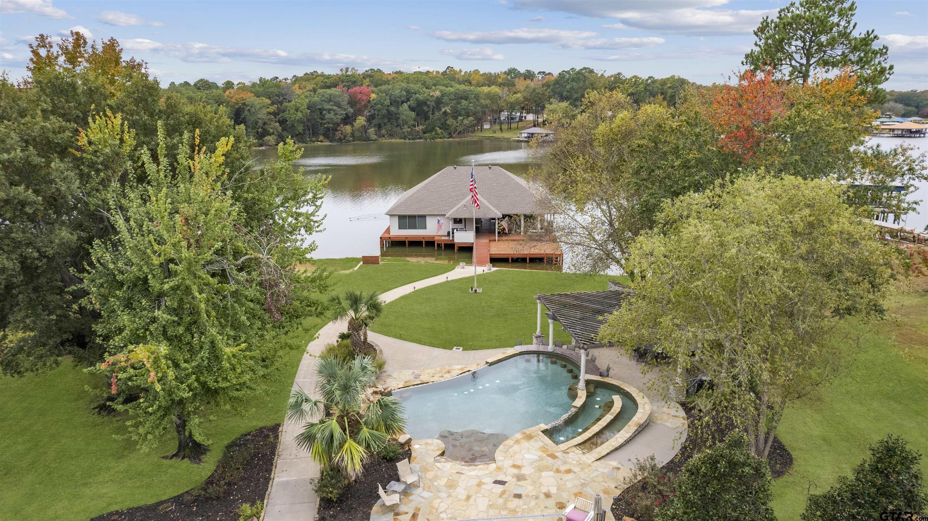 an aerial view of a house with outdoor space and a lake view in back