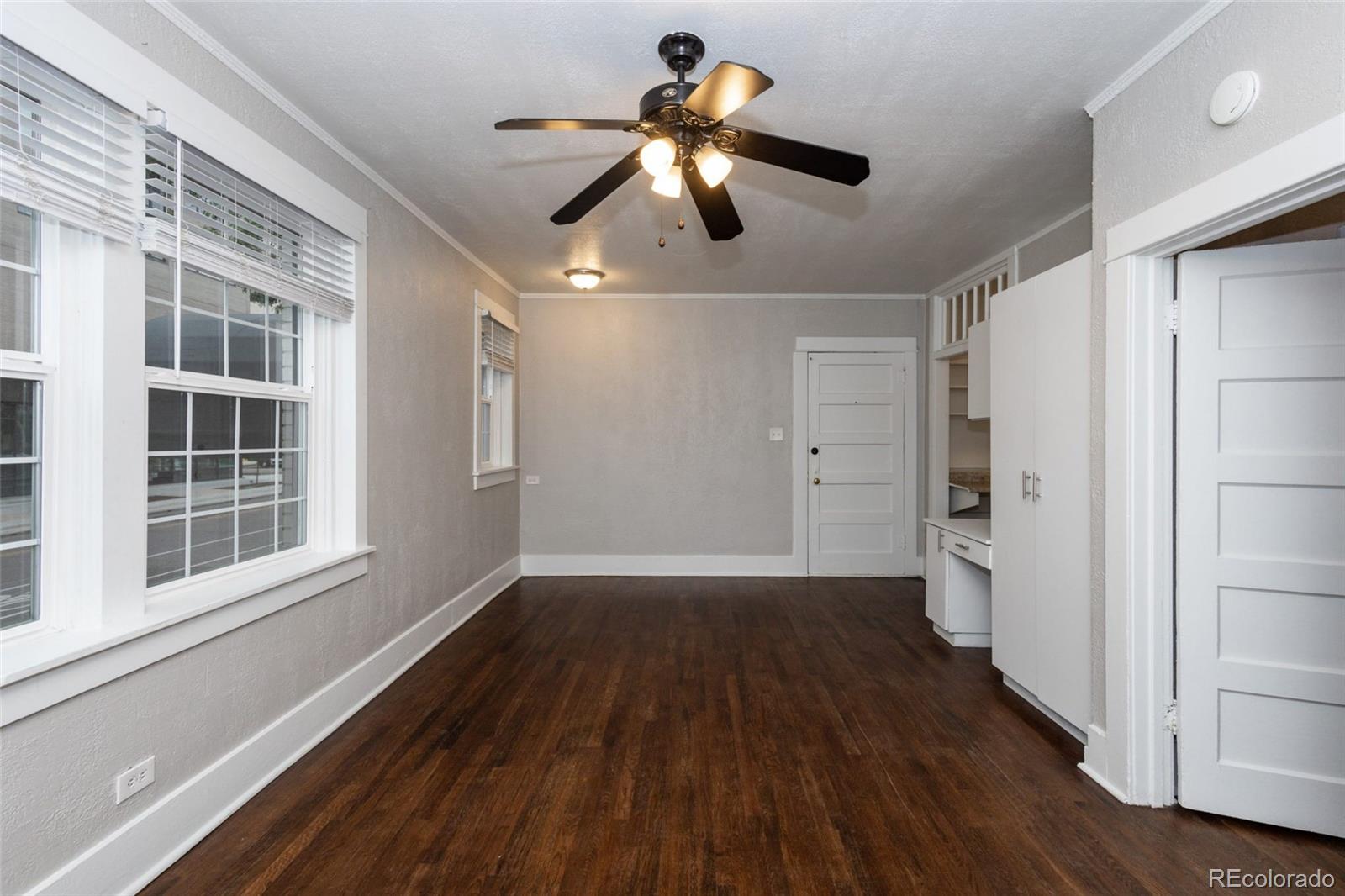 a view of an empty room with wooden floor and a window