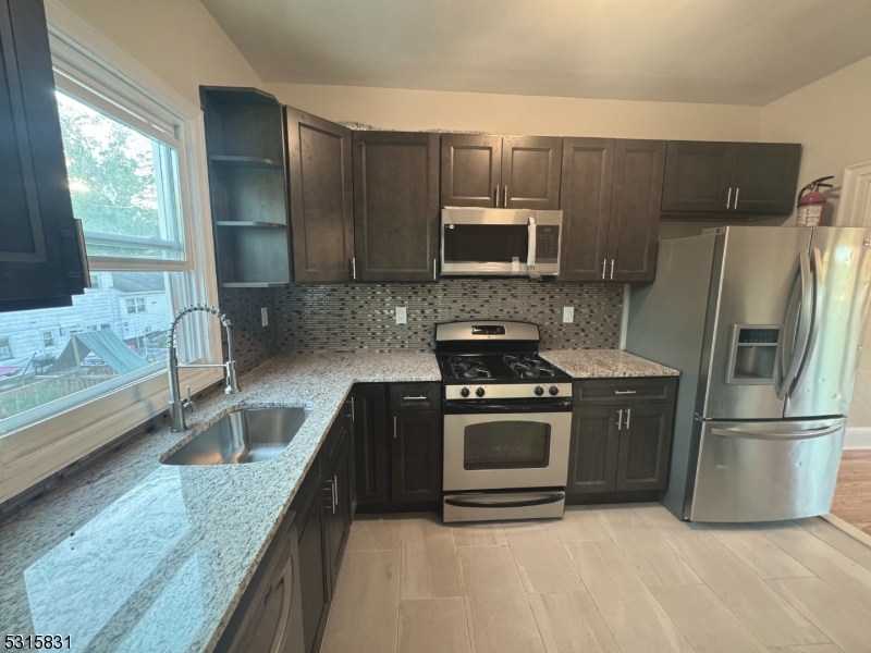 a kitchen with granite countertop a refrigerator stove and microwave