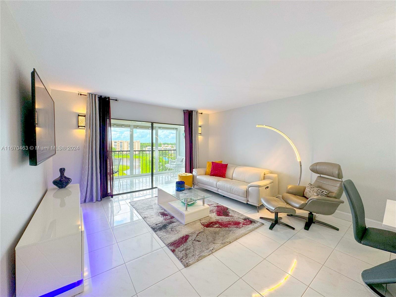 a living room with furniture a flat screen tv and a floor to ceiling window