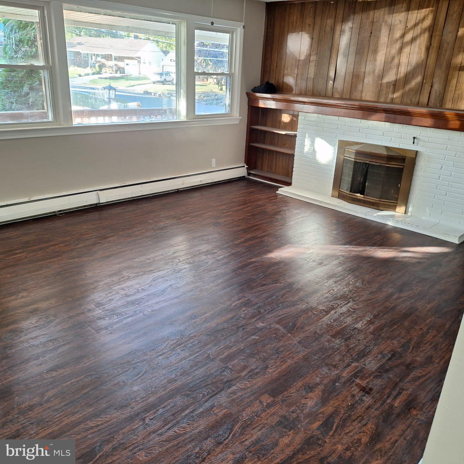 an empty room with wooden floor cabinet and windows