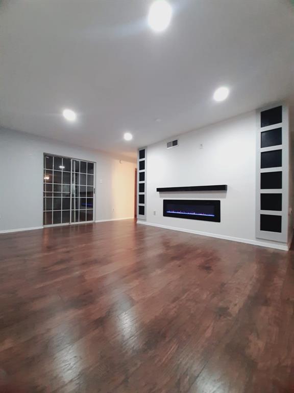 a view of empty room with wooden floor and windows