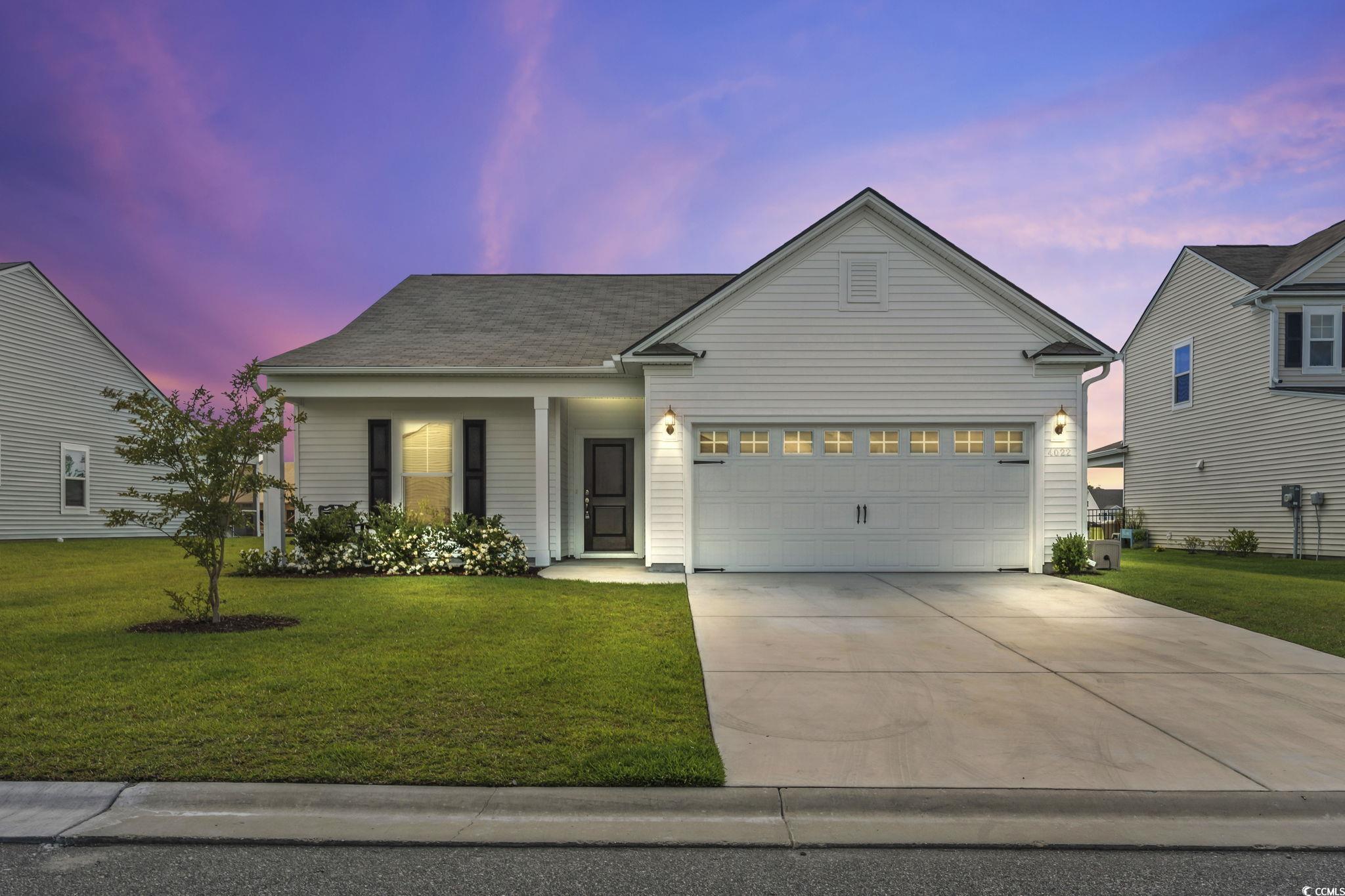 View of front facade featuring a garage and a lawn