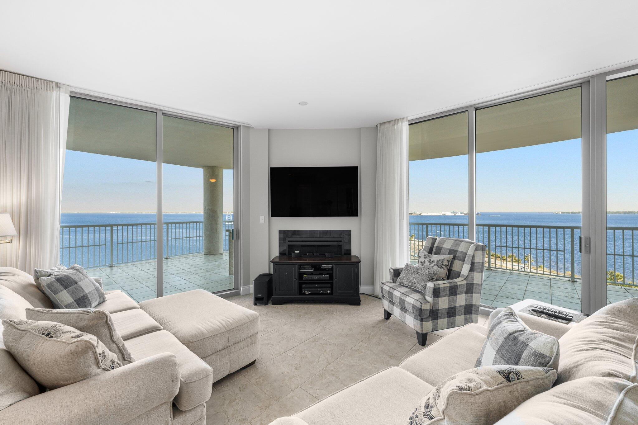 a living room with furniture a flat screen tv and a floor to ceiling window