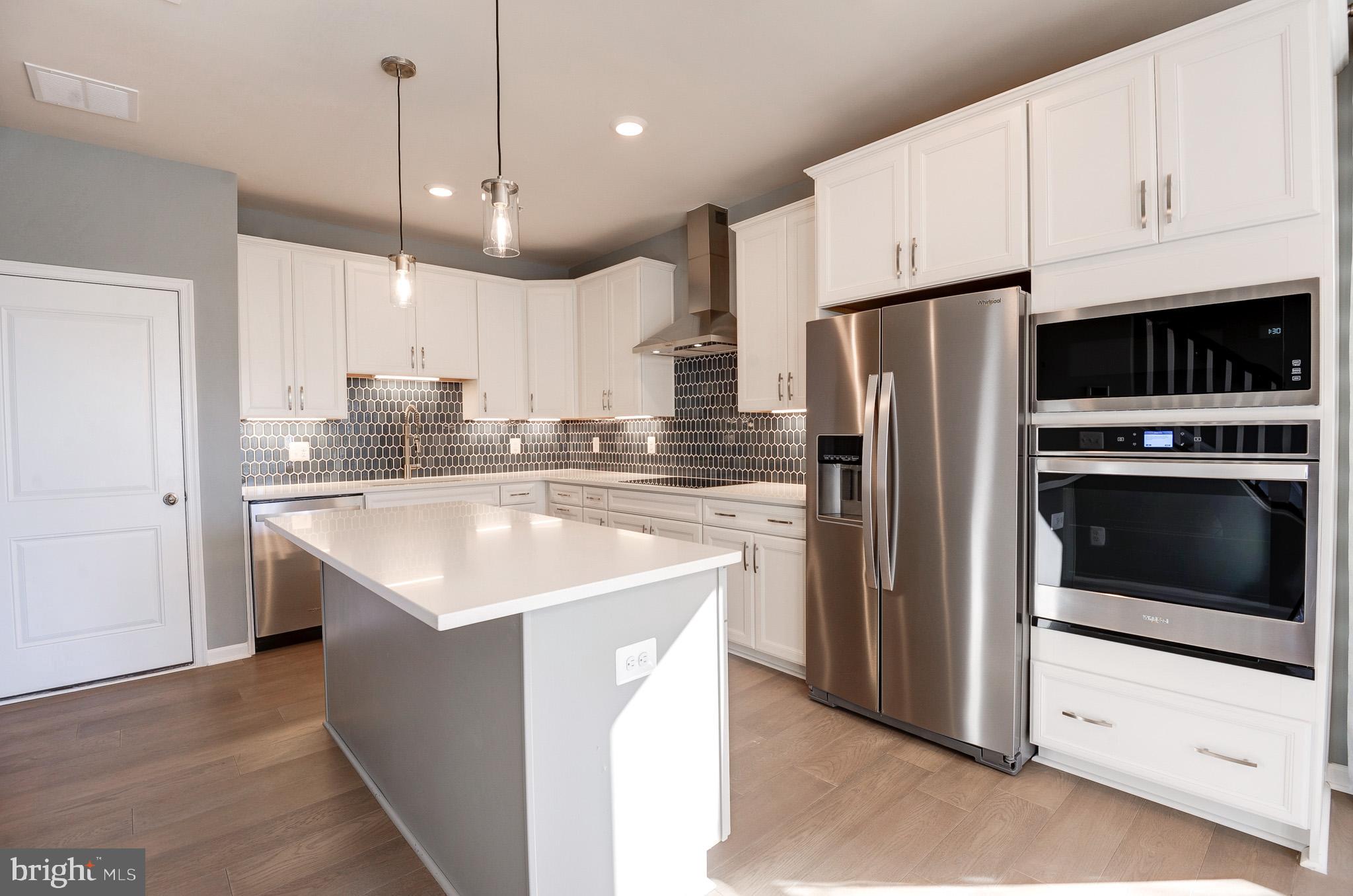 a kitchen with stainless steel appliances a refrigerator a stove a sink and white cabinets