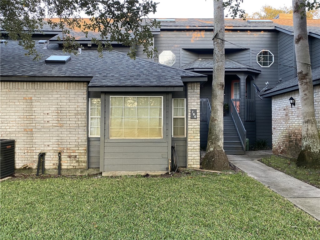 a view of a brick house with a small yard and large tree