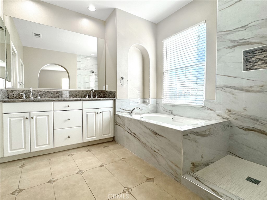 a bathroom with a granite countertop sink a mirror and a bathtub