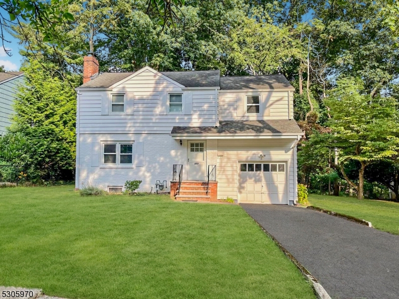 a front view of a house with a yard and trees