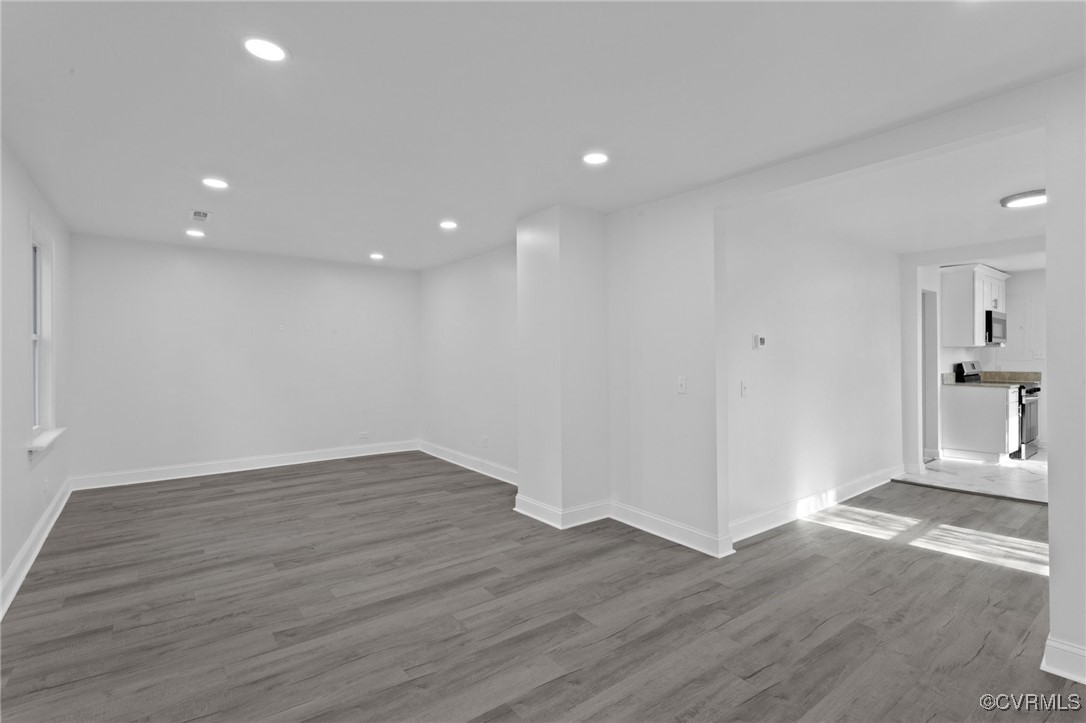 an empty room with wooden floor and windows