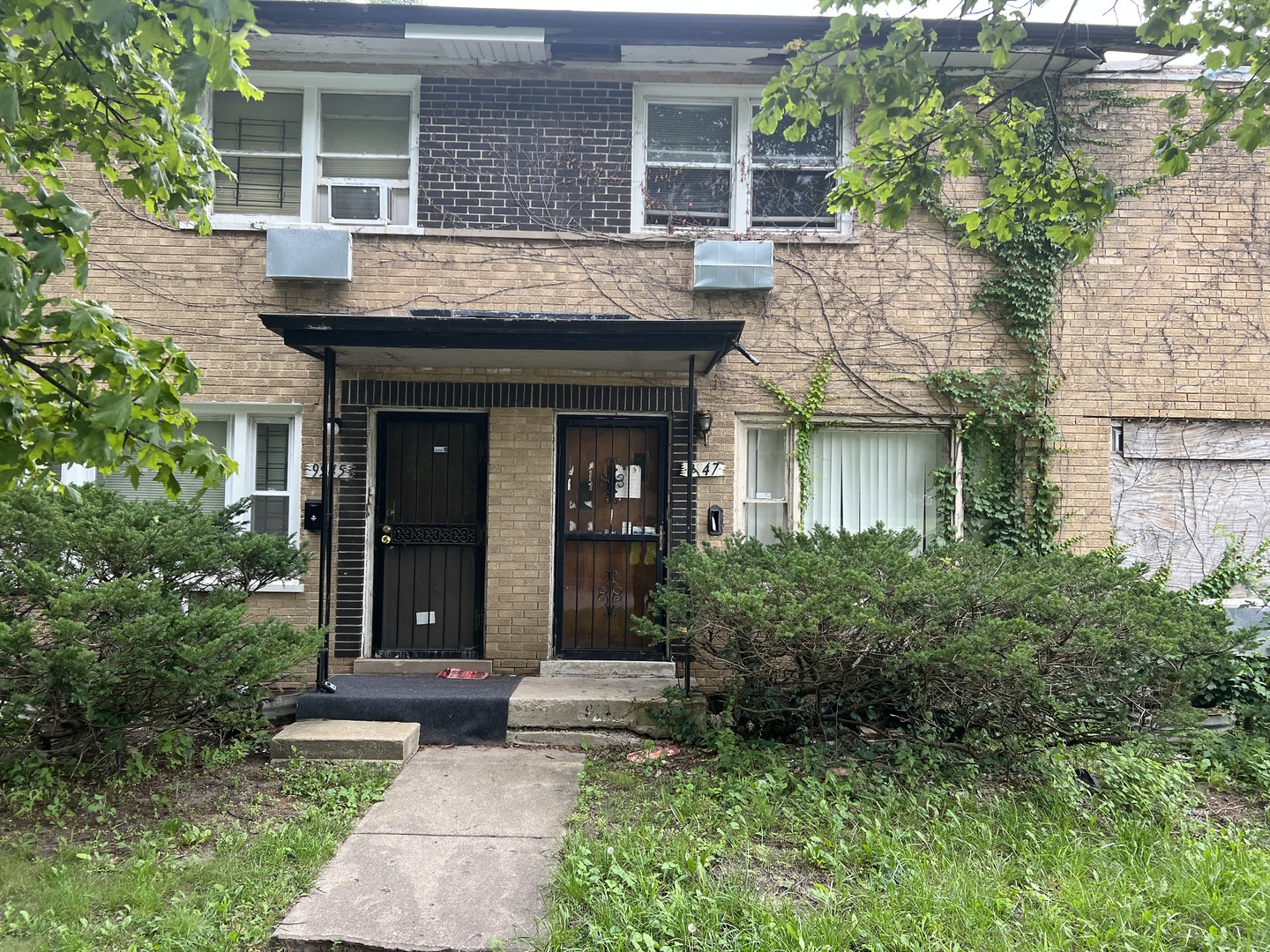 front view of a house with potted plants and a bench