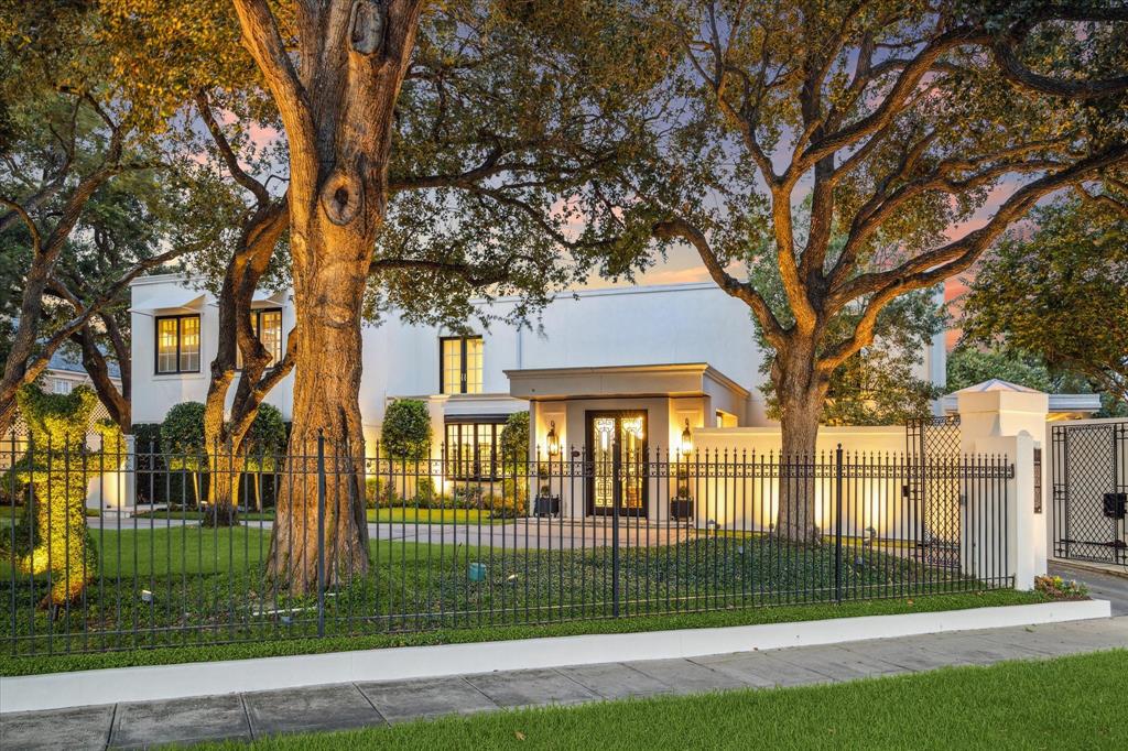 a view of a white house in a big yard with large tree