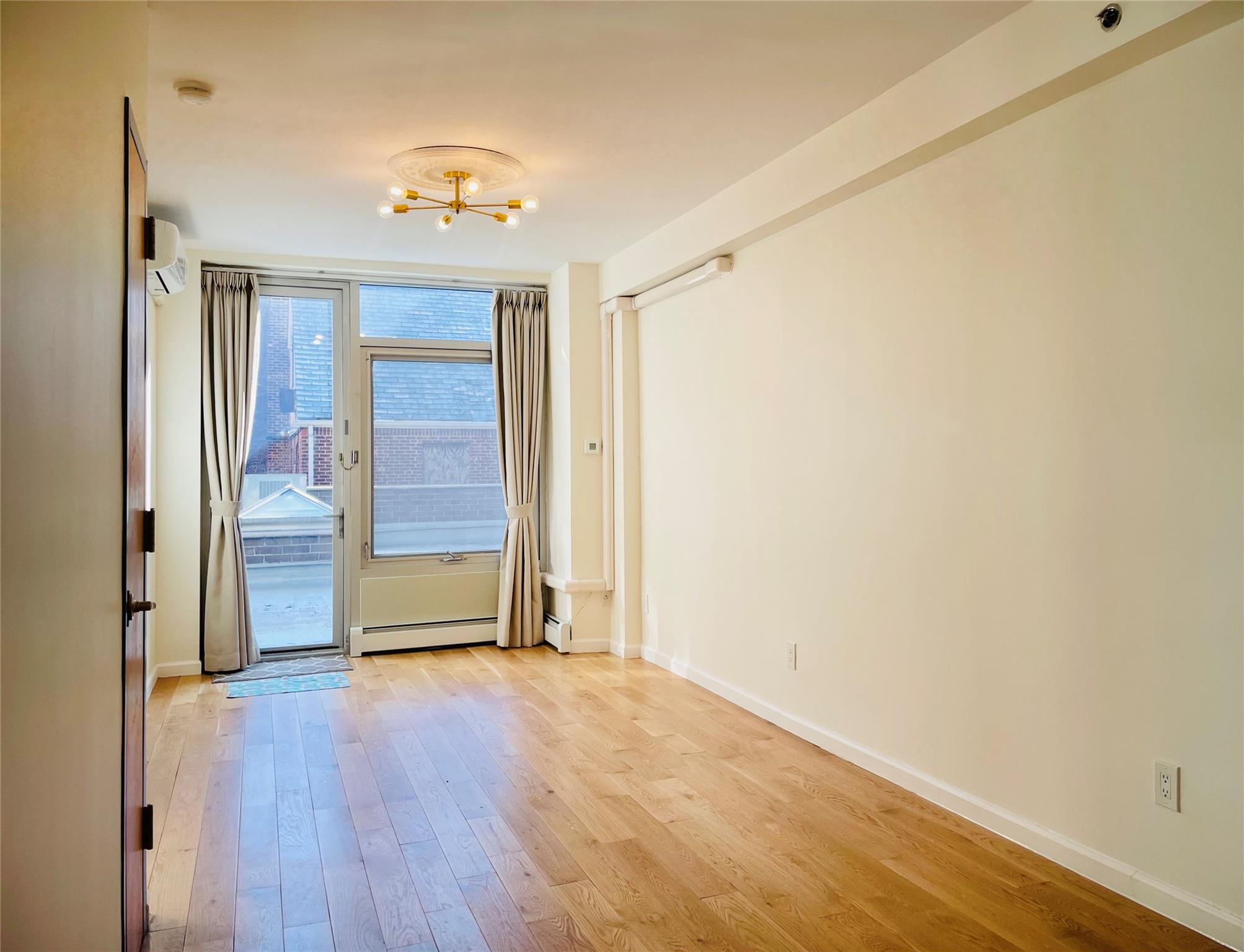 Entryway featuring light hardwood / wood-style floors, an inviting chandelier, a wall mounted air conditioner, and a baseboard heating unit