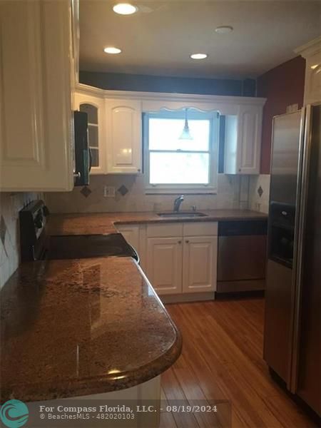 a kitchen with stainless steel appliances granite countertop a sink a stove and a refrigerator