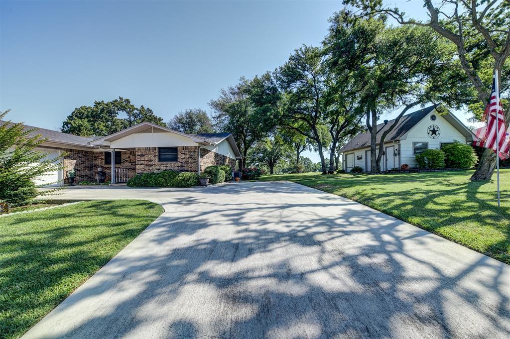 a view of house with yard street and trees in the background