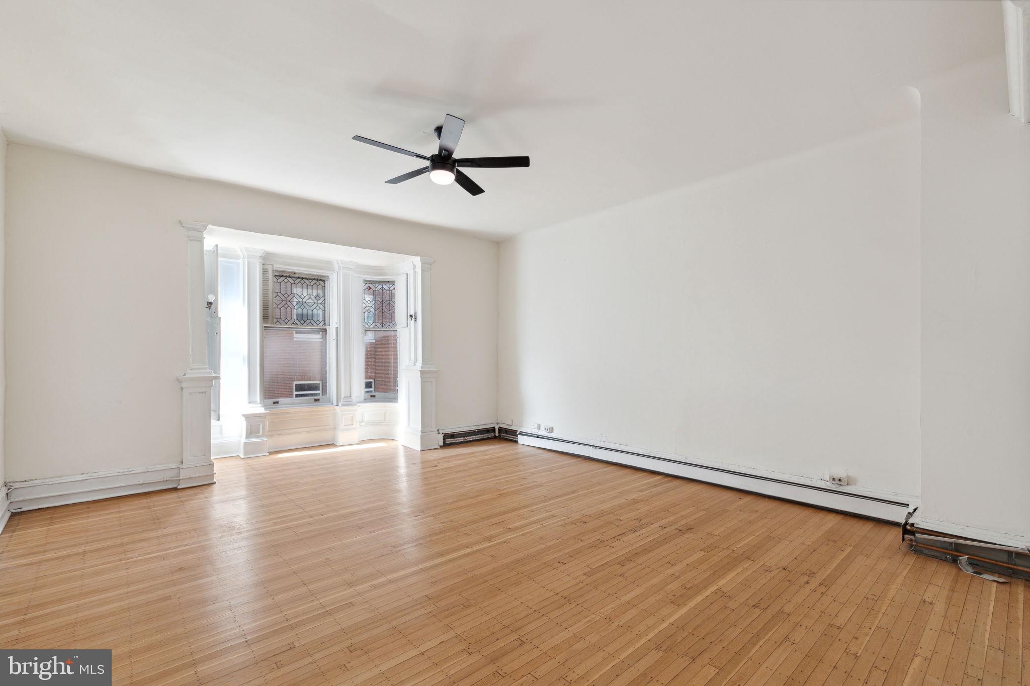 a view of empty room with wooden floor and fan