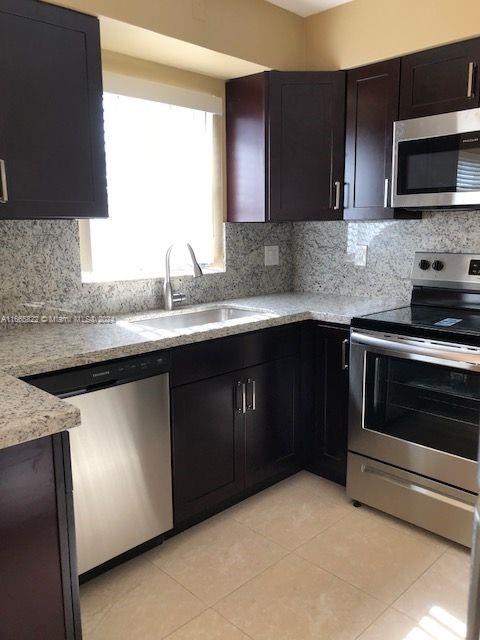 a kitchen with stainless steel appliances granite countertop a stove a sink and a microwave